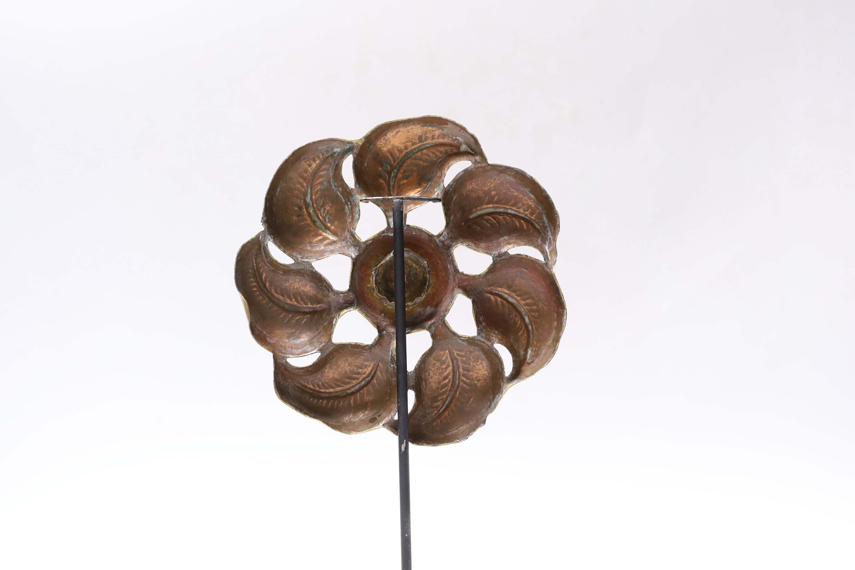 An embossed gilt metal flowerhead, centred by a blue glass cabochon